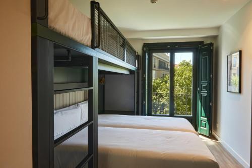 马德里LATROUPE Prado Hostel的一间卧室设有两张双层床和一扇窗户。