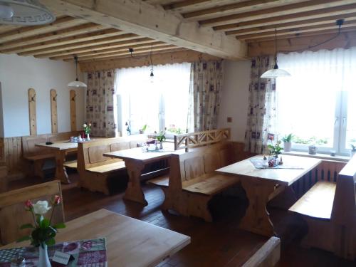 默尼希基兴Alpengasthof Fernblick的餐厅设有木桌、长凳和窗户。