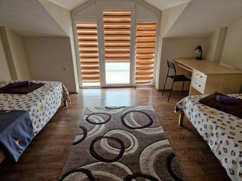 盖夫盖利亚Town Square House的一间卧室配有两张床、一张桌子和一张地毯。