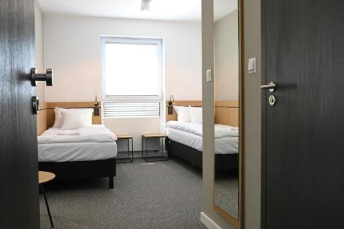 拉辛Hotel Parrot的小房间设有两张床和窗户