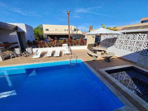 阿瓦雷Hotel Pousada Paraiso Avaré的一个带椅子和桌子的游泳池以及一把遮阳伞