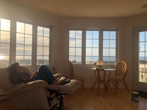 TracadiePhare des Dunes Lighthouse的两位女士躺在带窗户的客厅的沙发上