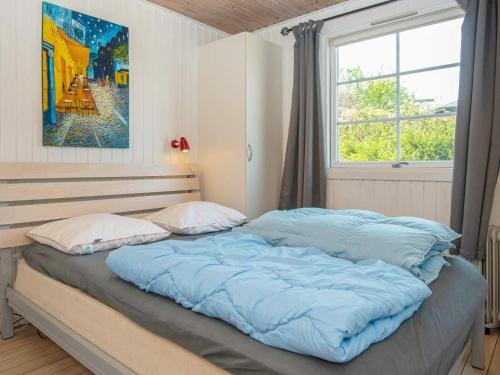 莱姆维Holiday home Lemvig XXXVIII的一间卧室配有一张带蓝色床单的床和一扇窗户。