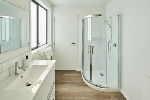 惠灵顿Brand New with Ocean Views的带淋浴和盥洗盆的白色浴室