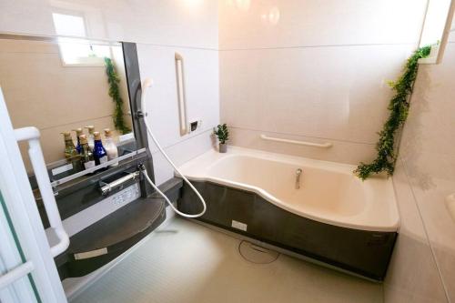 东京KODAKA Hotel TOKYO的浴室配有浴缸,墙上挂有常春藤
