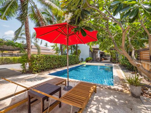 苏梅岛Lemon House apartment的红色遮阳伞和游泳池旁的长凳