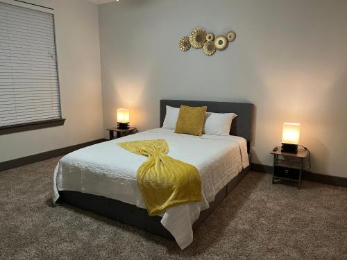 休斯顿Comfy Abode near Bush Airport的一间卧室配有一张带黄毯和两盏灯的床。
