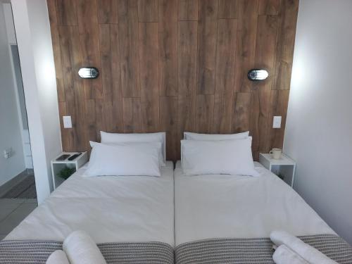 鲸湾港Walvis Bay Wind Beggars的一张带两个白色枕头和木制床头板的床