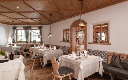 拉古多Hotel Kassian的餐厅设有白色的桌椅和木制天花板。