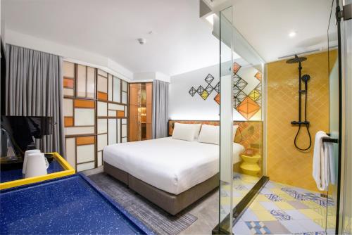 曼谷ibis Styles Bangkok Silom的一间卧室设有一张床和一个玻璃淋浴间
