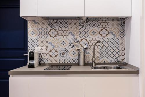 那不勒斯Eleonora Suites的一间带水槽和瓷砖墙的厨房