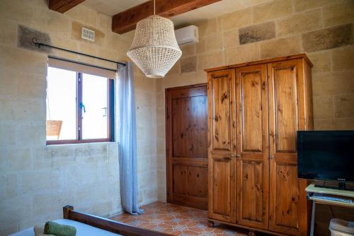 纳杜尔Laremi Gozo B&B的一间卧室设有大型木制橱柜和电视