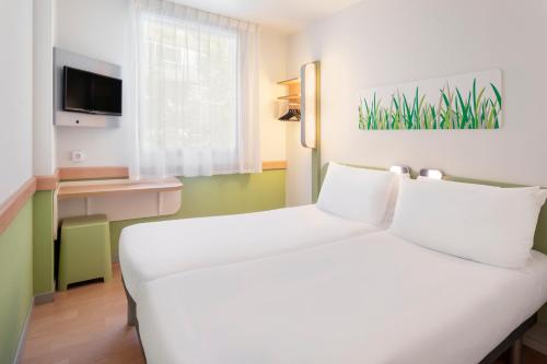 萨拉戈萨B&B HOTEL Zaragoza Plaza Mozart的一间酒店客房,配有白色的床和电视