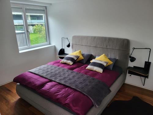 马蒂尼威尔Les Cubes的一间卧室配有一张大床,提供紫色床单和枕头