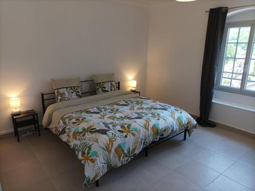 萨兰莱班O'Couvent - Appartement 66 m2 - 2 chambres - A523的一间卧室配有一张带五颜六色的被子和两盏灯的床。