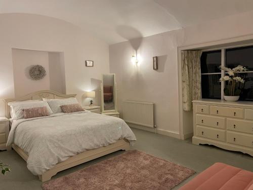 内尔斯沃思Cupcake Cottage: Quintessential Cotswold Cottage的一间卧室配有一张床、一个梳妆台和一扇窗户。