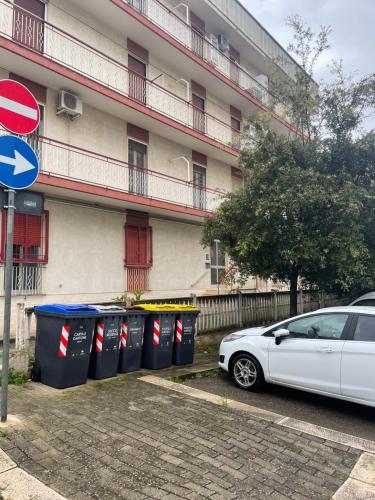 普蒂尼亚诺De Nicolò Home的把白色的汽车停在建筑物前面,里面放有垃圾桶
