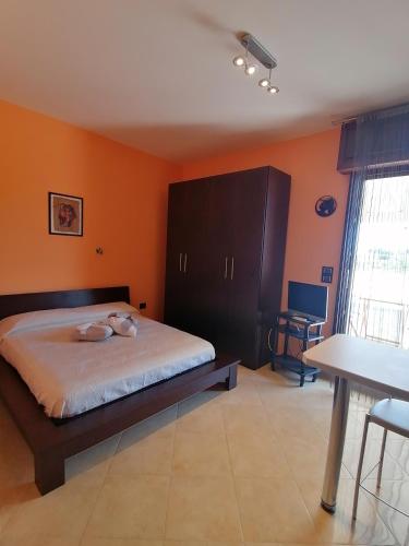 陶里萨诺Gagliardo House的一间卧室设有橙色的墙壁、一张床和一张桌子