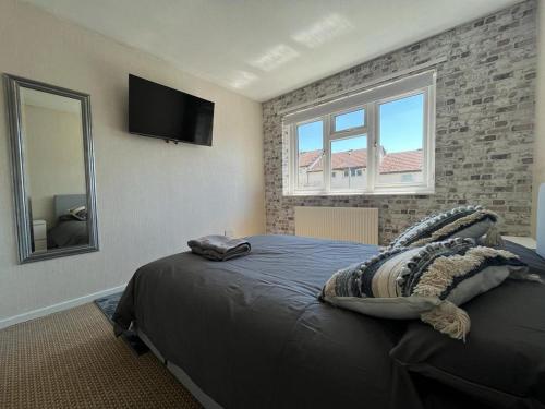 曼彻斯特Barnstaple Drive House的一间卧室设有一张大床和一台墙上的电视。