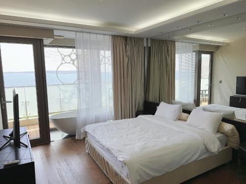 西归浦市Seopjikoji Oceanview Apartment的一间卧室设有一张床、浴缸和一个窗口