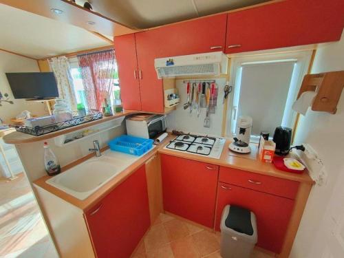 韦尔东的圣克鲁瓦Mobil home 6 personnes climatisation Sainte Croix du Verdon - Gorges du Verdon的一个带红色橱柜和水槽的小厨房