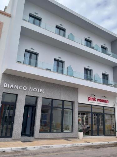 LakkíonBianco Hotel的一座白色的大建筑,有粉红色的女人酒店