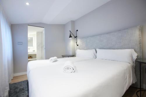 马德里U-Sense Madrid Santa Ana的一张白色的床,上面有两条毛巾