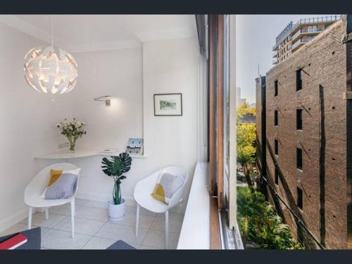 悉尼Stylish apartment in the heart of Potts Point的一间设有两把白色椅子和窗户的房间