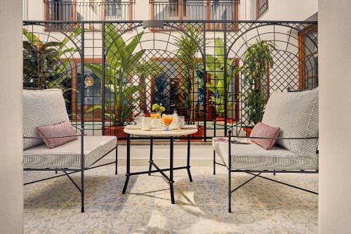 格拉纳达Seda Club Hotel - Small Luxury Hotels的一间房间,配有两把椅子和一张桌子,上面有饮料