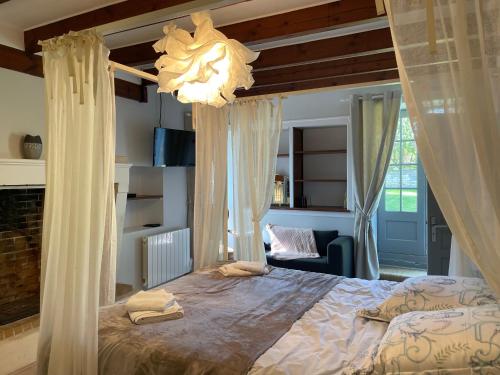 Le Domaine de la Gravette的一间卧室配有一张带窗帘和吊灯的床。
