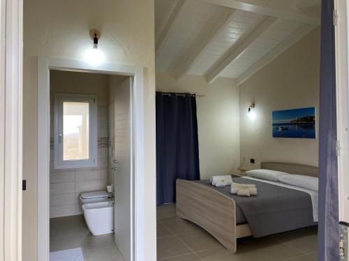 特乌拉达Is Arenas Biancas Agriturismo的一间卧室配有一张床,浴室设有卫生间
