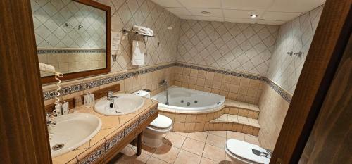 伊柳埃卡Castillo de Illueca的一间带两个盥洗盆、浴缸和卫生间的浴室