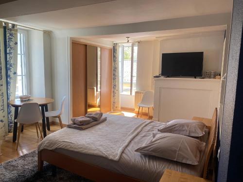 滨海科勒维尔La Suite Le Nôtre的一间卧室配有一张床、一张桌子和一台电视