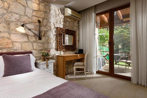 萨索斯尼科拉塔豪华别墅酒店的一间卧室设有一张床和石墙
