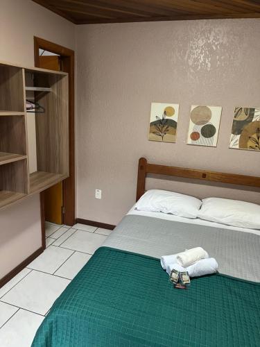 因贝Pousada da Praia Imbé的一间卧室配有一张带绿毯和毛巾的床
