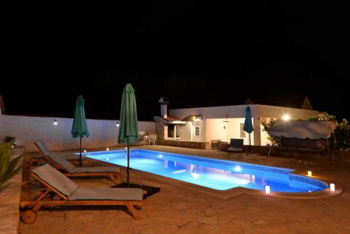Mala ČistaHouse Vidamo - Vacation home with swimming pool的游泳池在晚上配有两把椅子和遮阳伞