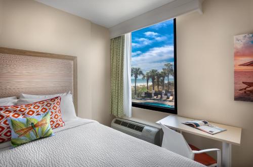 默特尔比奇Surfside Beach Oceanfront Hotel的一间卧室配有一张床、一张书桌和一个窗户。