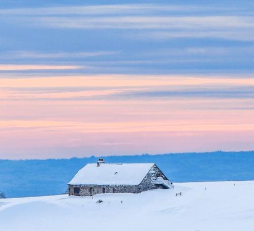 拉吉约勒Studio au cœur de Laguiole的雪地覆盖的天空中的一座古老的谷仓
