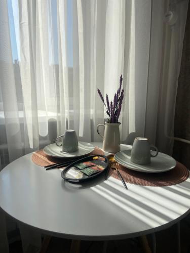 库斯塔奈Комфортабельные - Уютные апартаменты в Костанай Алтын Арман的白色的桌子,有两盘,花瓶