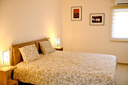 内坦亚Topnatanya的一间卧室配有一张床、两盏灯和一个窗户。