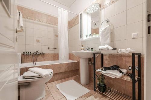 沃洛斯Luxury Beach House的浴室配有盥洗盆、卫生间和浴缸。