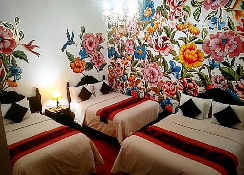 库斯科Casona Dorada Hotel Cusco的客房设有两张带花卉图案壁纸的床。