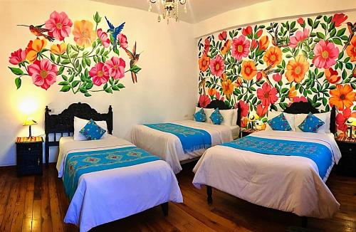 库斯科Casona Dorada Hotel Cusco的两张床位于带花卉壁画的客房内。