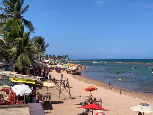 卡马萨里Casa Completa com piscina, 800m da praia de Jauá的海滩上有许多遮阳伞和水中的人