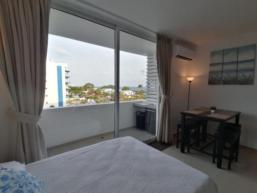 里奥阿托Playa Blanca SC的一间卧室配有一张床、一张书桌和一个大窗户