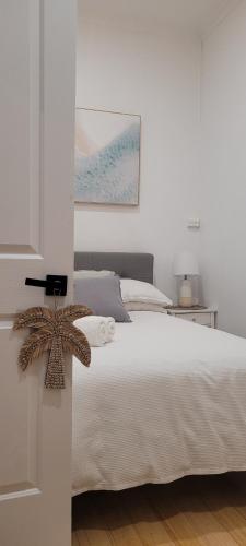 墨尔本Boutique Beach House in the HEART of St. Kilda的卧室配有白色的床和墙上的绘画作品