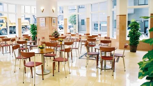 磐城Toyoko Inn Iwaki Ekimae的餐厅设有桌椅和窗户。