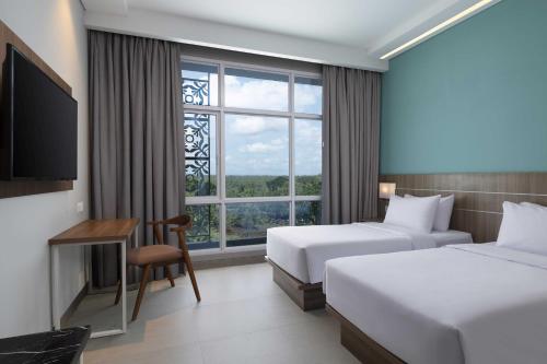 SiyonokulonHotel Santika Gunungkidul的酒店客房设有两张床和窗户。