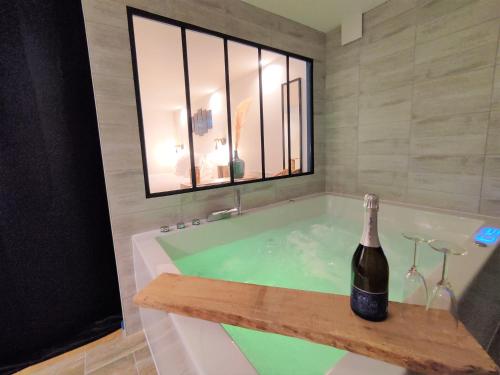 维希Maison de ville, SPA Balnéo, 2 suites parentales的浴缸内备有一瓶香槟
