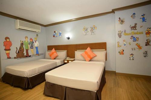 碧瑶金松酒店的一间卧室配有两张壁挂卡通人物的床